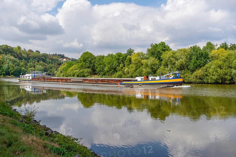 Cargo ship on a river at summer time in sunny ambiance
