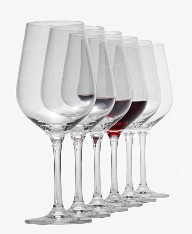 Some wine glasses standing consecutive in a row in white back, one partly filled with red wine
