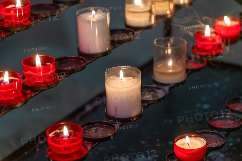 Closeup shot of some votive candles on a votive candle rack in dark ambiance