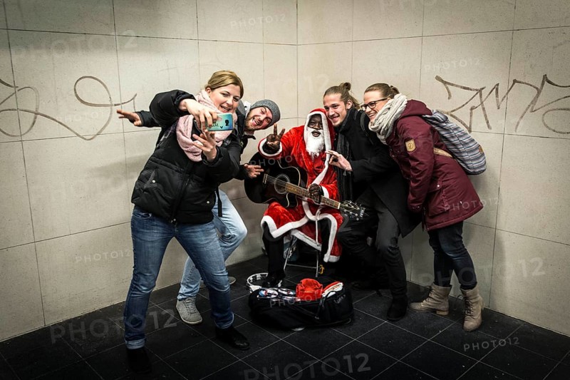 DEU Germany Germany Berlin A dark-skinned singer dressed as Father Christmas plays the guitar in the Stadtmitte underground station