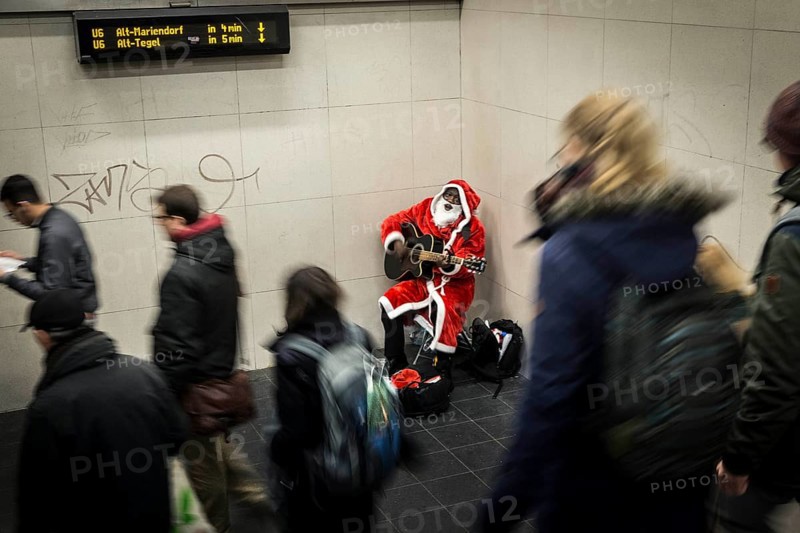 DEU Germany Germany Berlin A dark-skinned singer dressed as Father Christmas plays the guitar in the Stadtmitte underground station