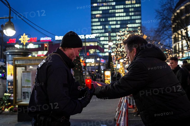 DEU Germany Germany Berlin The second day after the attack on the Christmas market at the Gedächniskirche. A policeman takes a candle from a passer-by to place it at a place of mourning