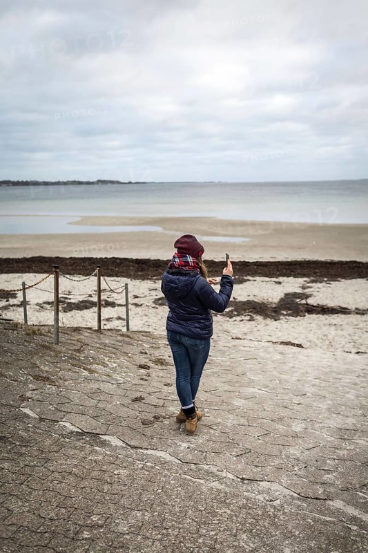 DEU Germany Germany Flensburg A woman takes a photo with her mobile phone on the beach at Holnis