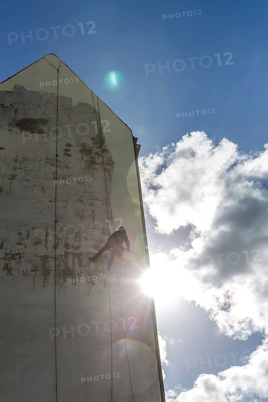 DEU Germany Germany Berlin A worker painting a façade while hanging from a rope
