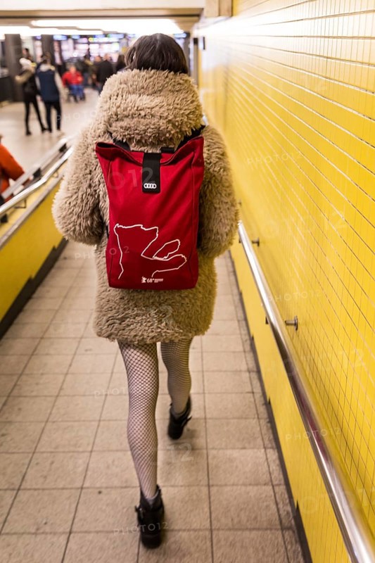 DEU Germany Germany Berlin A woman wears a Berlinale backpack with a plush coat and fishnet stockings through the B-level of Bahnhof Zoo