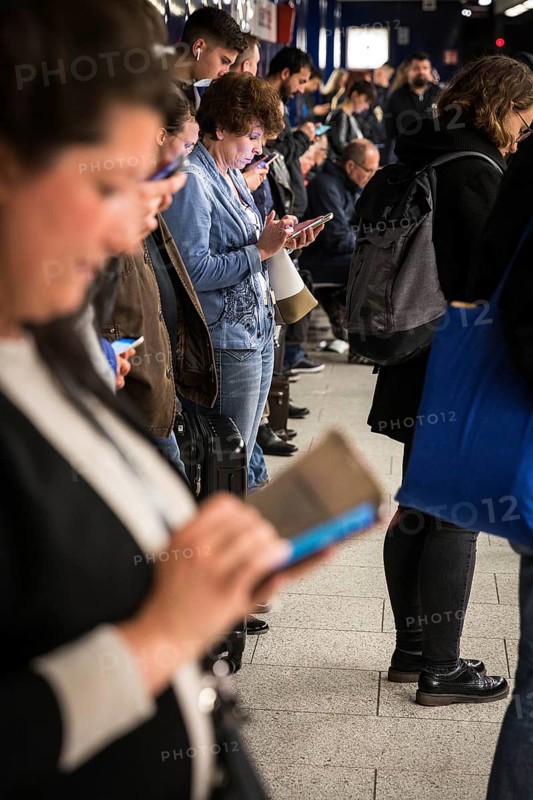 DEU Germany Germany Berlin Passengers look at their mobile phones while waiting for the train at Osloer Straße underground station