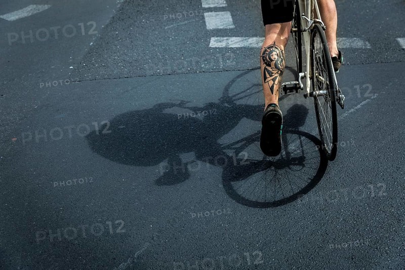 DEU Germany Germany Berlin A huge tattoo adorns the calf of a cyclist just starting out on Potsdamer Platz