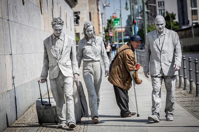 DEU Germany Germany Berlin Three people painted in grey walk along the wall of the Ministry of Finance. A beggar who crosses their path looks after them. A snapshot taken during a photo shoot for the 1000 Gestalten project on Niederkirchner Straße in Mitte