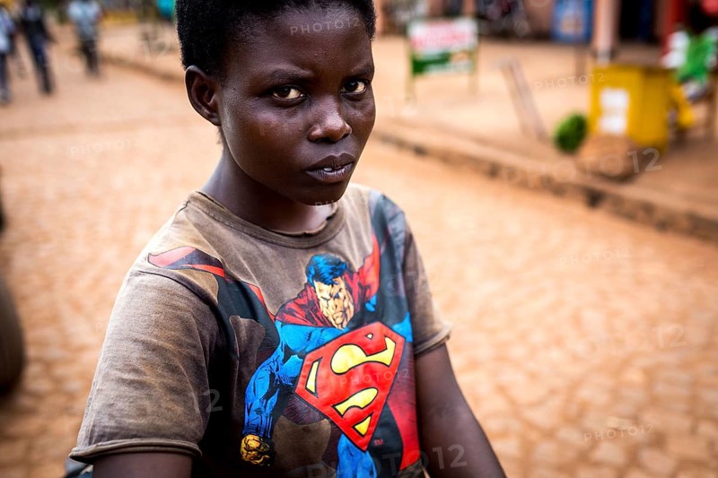 RWA RWANDA Rwanda Kayonza A young woman with a bicycle shows her Superman shirt