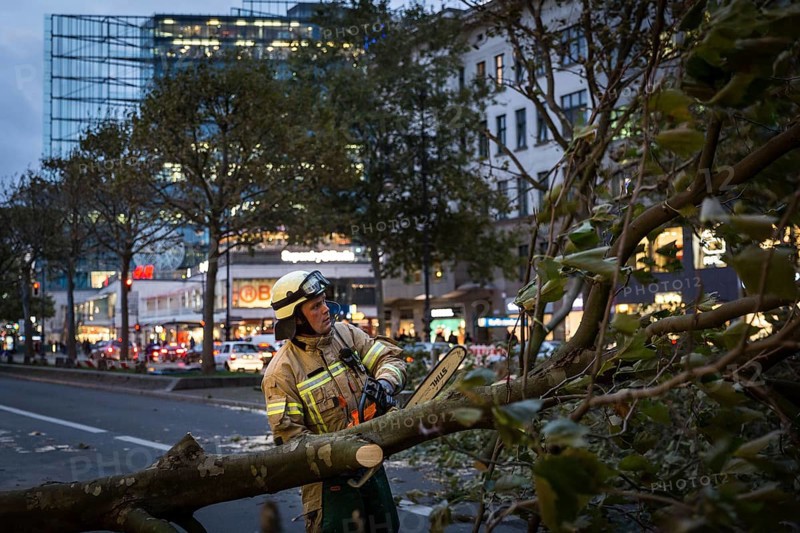 DEU Germany Germany Berlin Fire brigade operation on Kurfürstendamm. Storm Xavier had caused trees to fall onto the street. Firefighter saws tree into pieces
