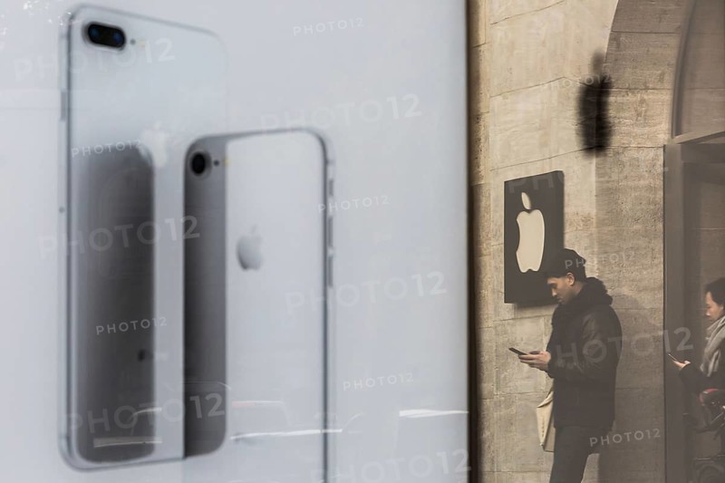 DEU Germany Germany Berlin People with smartphones leave the Applestore on Kurfürstendamm. They are reflected in the outdoor advertising for the new iPhone