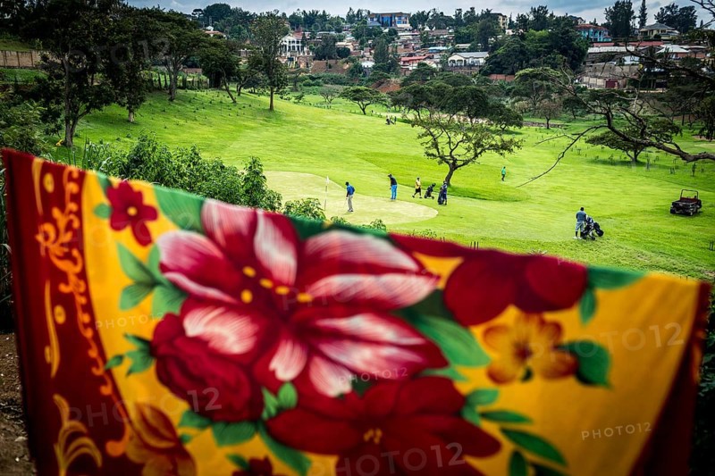 RWA RWANDA RUANDA Kigali Rwandans play on a centrally located golf course at lunchtime. The ceiling belongs to residents of neighbouring huts
