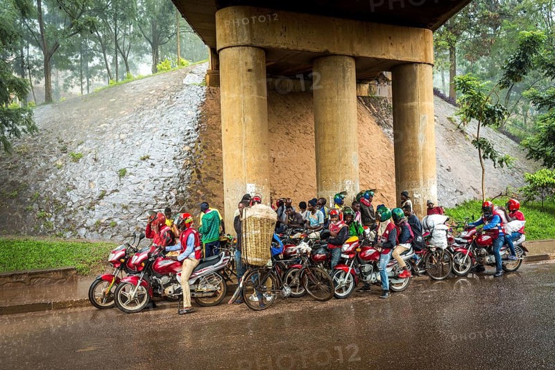 RWA RWANDA RUANDA Kigali Taxi drivers with motorbikes and bicycles wait under a bridge for the end of a rainstorm