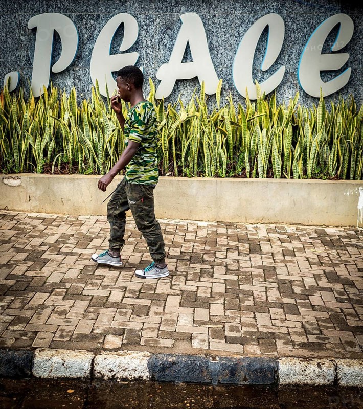 RWA RWANDA RUANDA Kigali A man in camouflage fashion passes a Peace font in the Kiyovu banking district