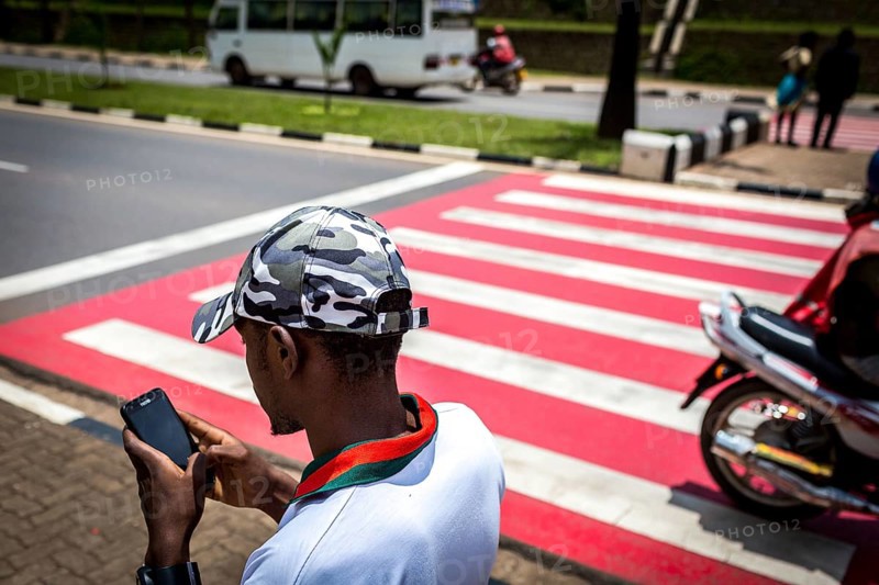 RWA RWANDA RUANDA Kigali A youth with a camouflage baseball cap looks at his mobile phone while walking along the street