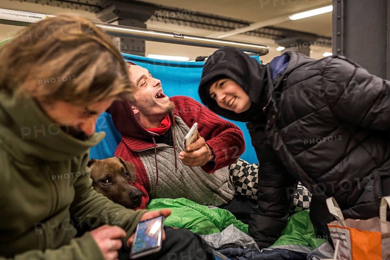 DEU Germany Germany Berlin Homeless people spend the night in a passageway at Lichtenberg underground station. Like Moritzplatz, the station has been made available for overnight stays by the BVG during the winter months.homeless people with their smartphones