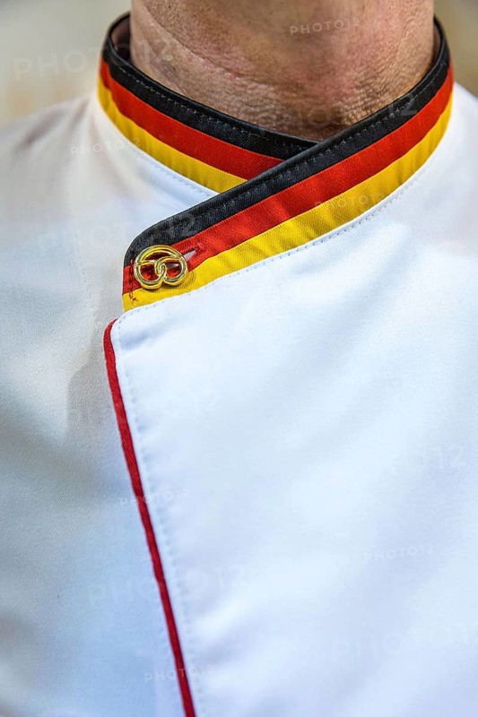 DEU Germany Germany Berlin Scene of the Green Weeks, the annual trade fair for food, agriculture and ecology. A baker with a collar in the German colours and a golden pretzel