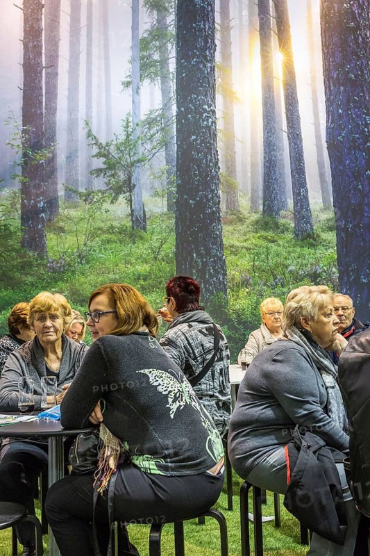 DEU Germany Germany Berlin Scene of the Green Weeks, the annual trade fair on food, agriculture and ecology. Visitors take a break in front of a photo wall with forest