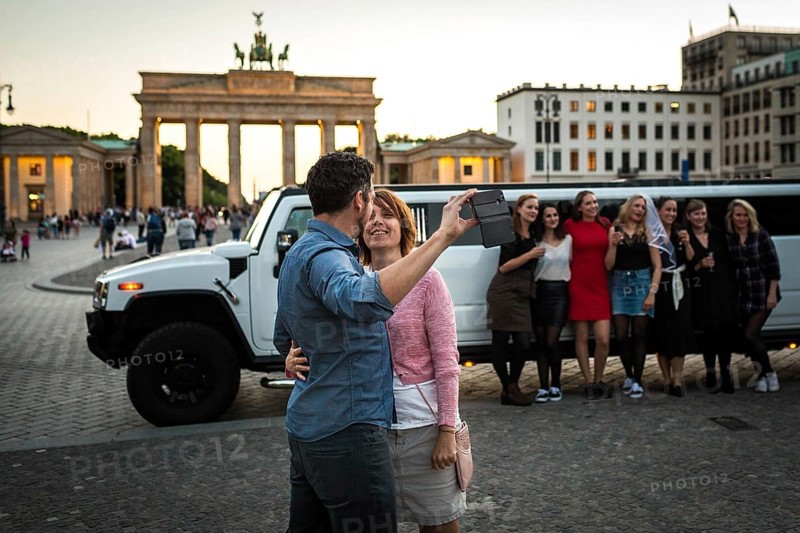 DEU Germany Germany Berlin Young woman pose with a rented stretch limousine in front of the Brandenburg Tor, where a couple takes a selfie