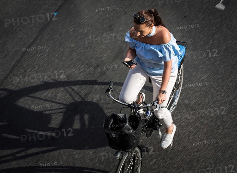 DEU Germany Germany Berlin Scene with cyclists on Schlossstraße in Steglitz. Woman with mobile phone while riding