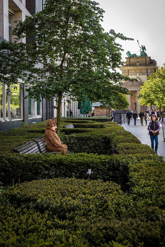 DEU Germany Germany Berlin A man in a bear costume waits on a bench for the attention of passing tourists near the Brandenburg Tor