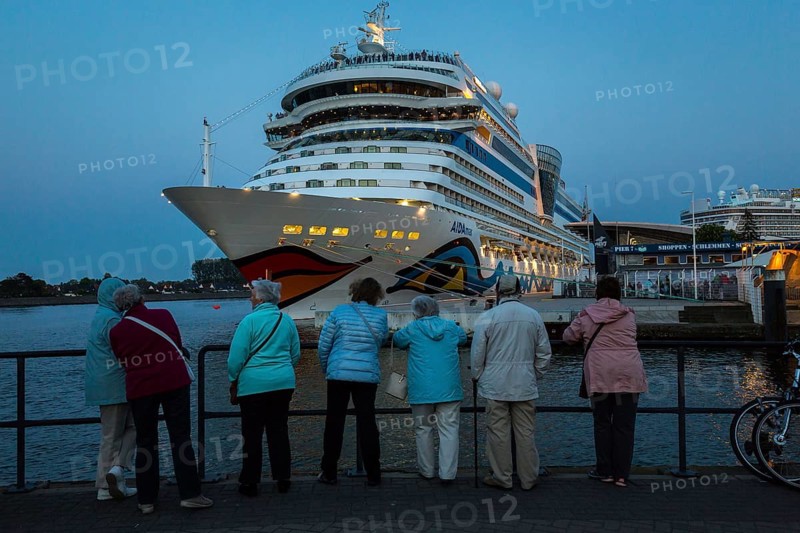 DEU Germany Germany Warnemünde Scene on the beach of Warnemünde with a large harbour for cruise ships on the Baltic Sea. Visitors admire the Aida