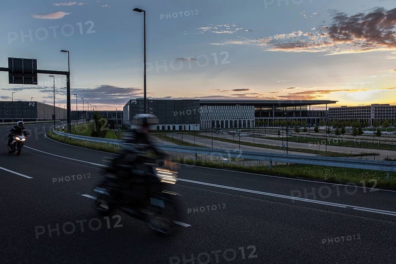DEU Germany Germany Berlin Motorbikes pass the future BER Berlin-Brandenburg airport at sunset