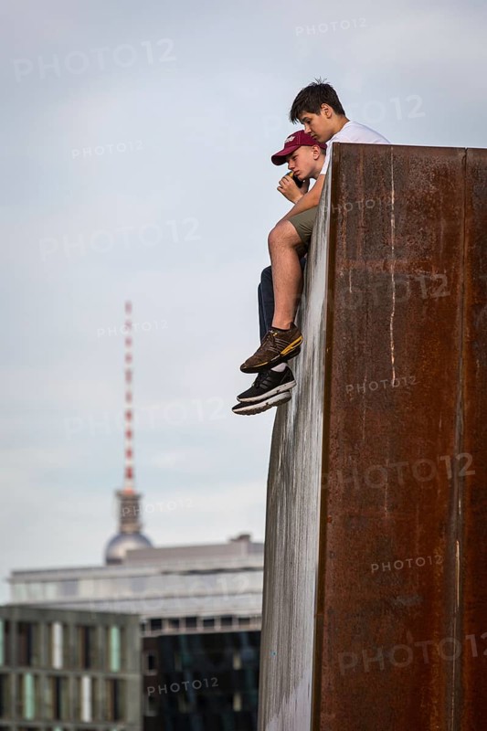 DEU Germany Germany Berlin In summer temperatures, two young people sit on a wall on the Spreebogen and enjoy the view
