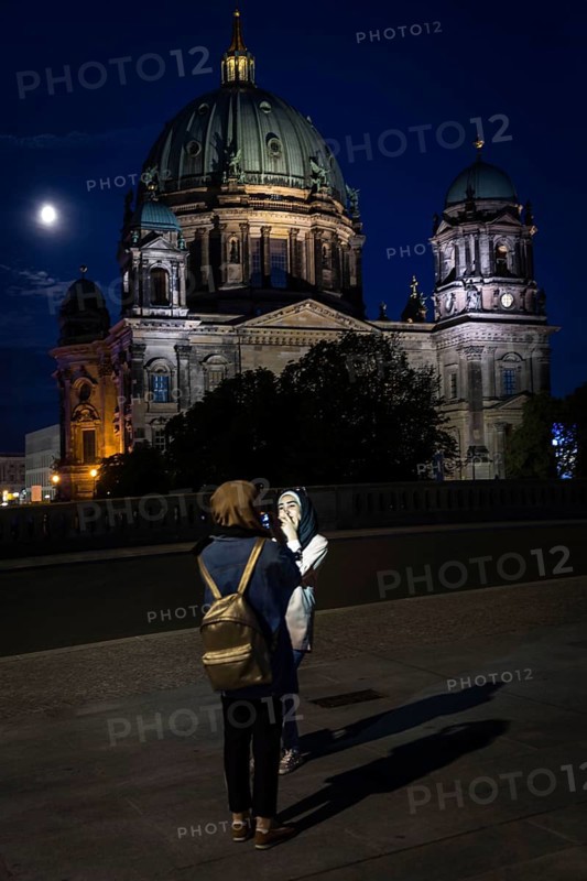 DEU Germany Germany Berlin Women photographing themselves in front of Berlin Cathedral with the moon at the blue hour