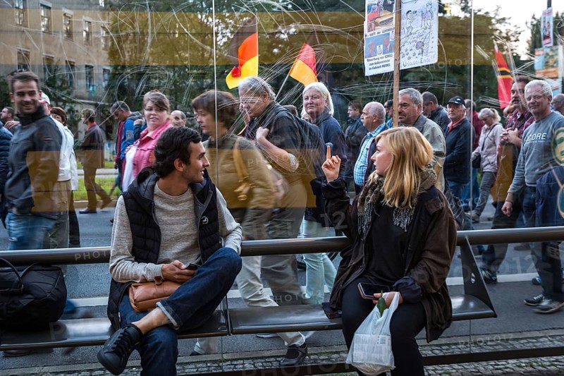 DEU Germany Germany Dresden Pegida demonstration in the city centre.woman of the demonstration shows the middle finger to a woman at a tram stop