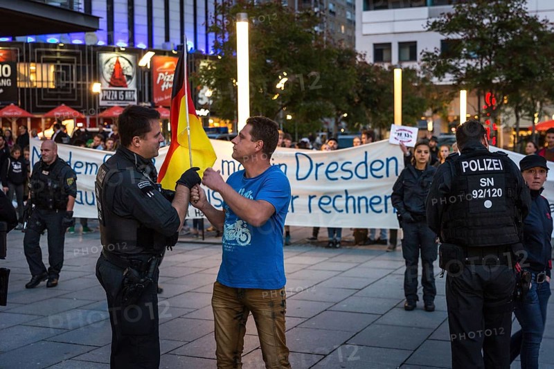 DEU Germany Germany Dresden Pegida demonstration in the city centre. Counter-demonstration in the pedestrian zone Police officer admonishes Pegida supporter who provokes with German flag