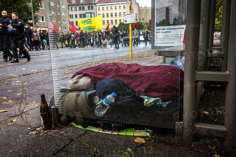 DEU Germany Germany Berlin Demonstration against rent increases and gentrification Protest march passes a homeless man sleeping in a bus stop in Kreuzberg
