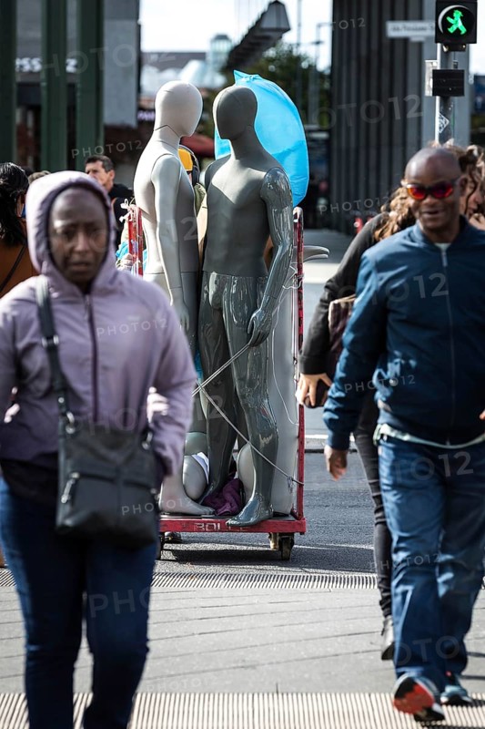 DEU Germany Germany Berlin Pedestrians crossing a street at Potsdamer Platz where mannequins are being transported in the background