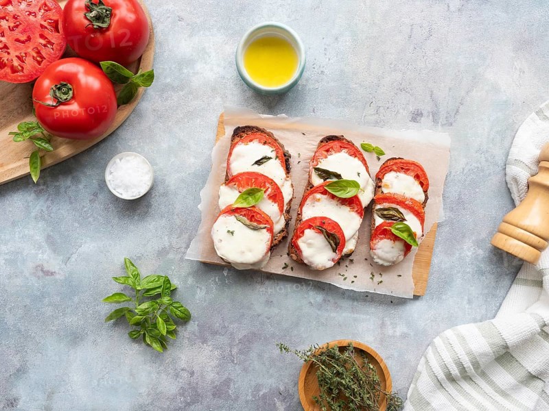 Caprese bruschetta with fresh ingredients on a light gray background, ready to eat