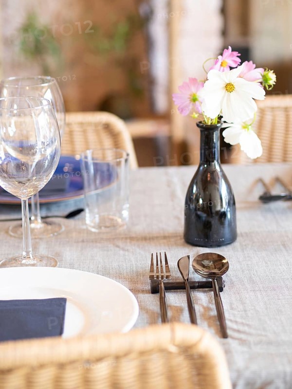 Decorated restaurant table with a flower vase, clean plates, glasses, and modern cutlery