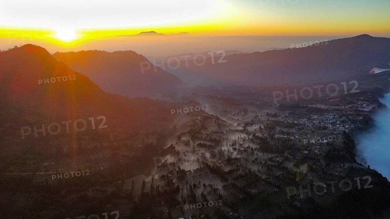 Fog lying between the mountains at sunrise, photograped with a drone