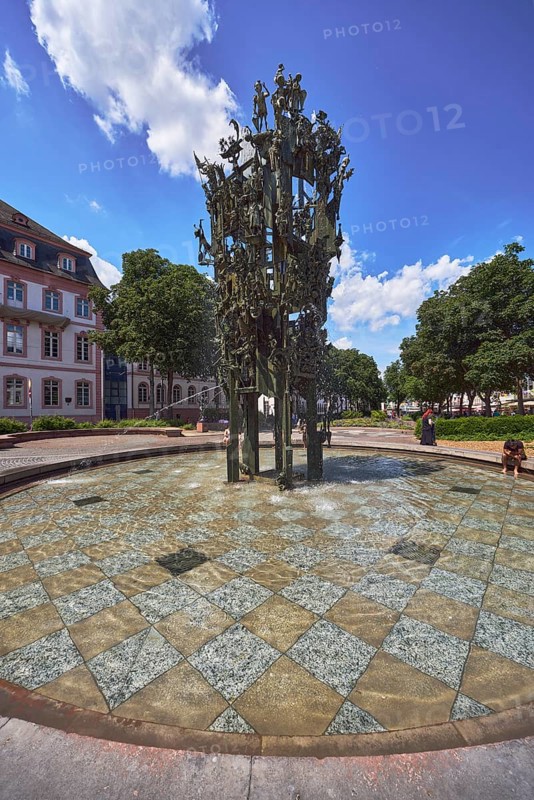 Shrove Tuesday fountain, fountain with bronze sculptures, sculptor Blasius Spreng, architect Helmut Gräf, general architecture, houses, pedestrians and seated people as secondary motifs, trees, blue sky, cumulus clouds, Schillerplatz square, Mainz, state capital, district-free city, Rhineland-Palatinate, Germany