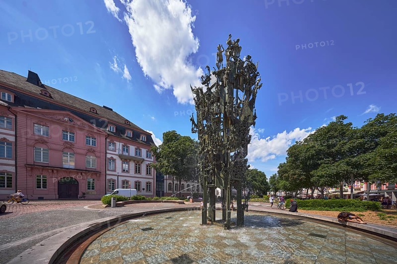 Shrove Tuesday fountain, fountain with bronze sculptures, sculptor Blasius Spreng, architect Helmut Gräf, general architecture, houses, pedestrians and seated people as secondary motifs, trees, blue sky, cumulus clouds, Schillerplatz square, Mainz, state capital, district-free city, Rhineland-Palatinate, Germany