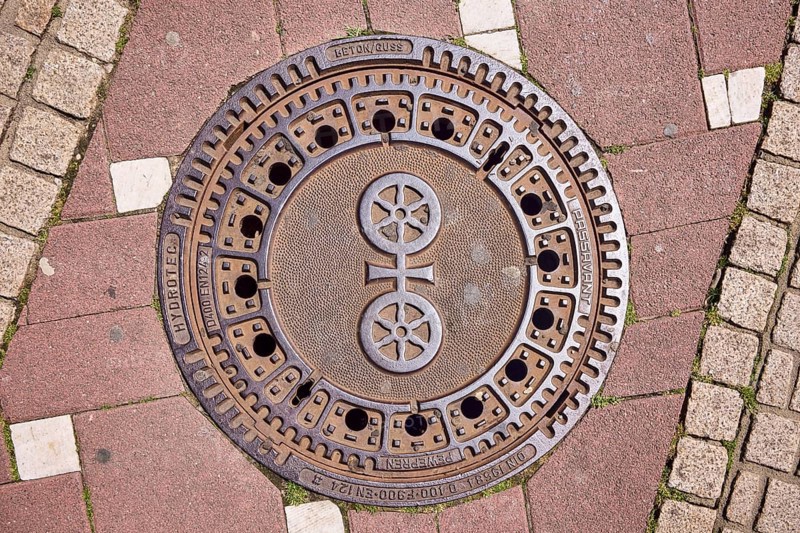 Manhole cover, city coat of arms, sidewalk made of concrete paving stones and paving stones with pattern, sunny, Mainz, state capital, district-free city, Rhineland-Palatinate, Germany