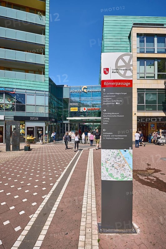 Stele with location sign, Roman passage, shopping center, general architecture, modern building, commercial building, shop, retail, sidewalk made of concrete paving stones and paving stones with pattern, pedestrian zone, trees, blue sky, cloudless, Cardinal-Volk-Platz, Mainz, state capital, district-free city, Rhineland-Palatinate, Germany