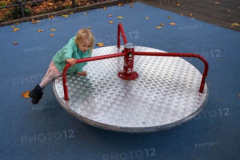 Outdoor shot, little girl, child, 4 years, blonde, playing on carousel, children's playground, slipping off, danger, autumn leaves, autumn, Stuttgart, Baden-Württemberg, Germany