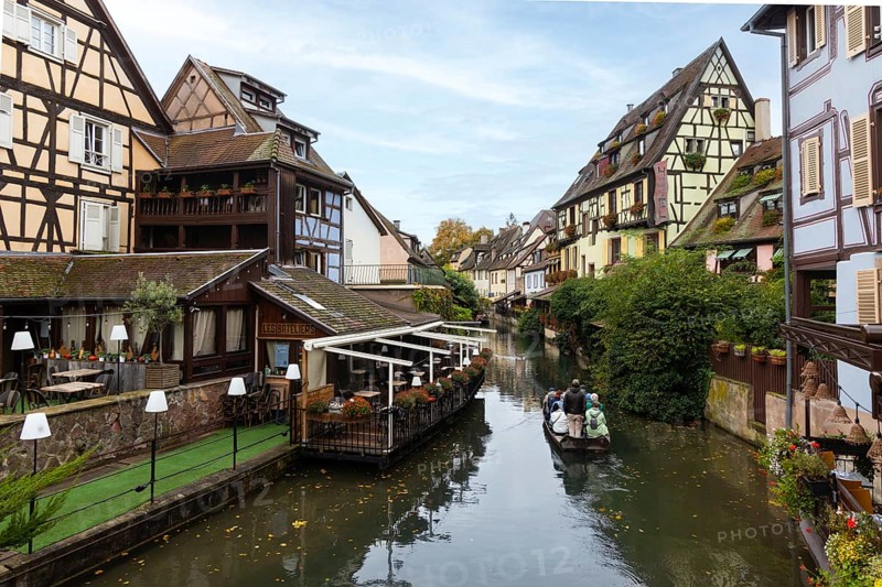 Traditional houses along a river, here called the little Venice, with tourists visiting Colmar on a boat, Alsace, France