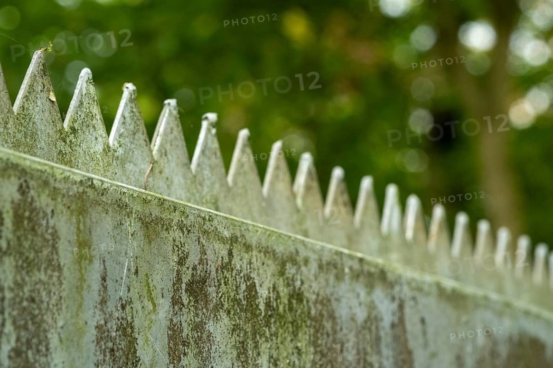 Borken, NRW, Germany, Metal security fence with sharp spikes against green bokeh creating a protective barrier