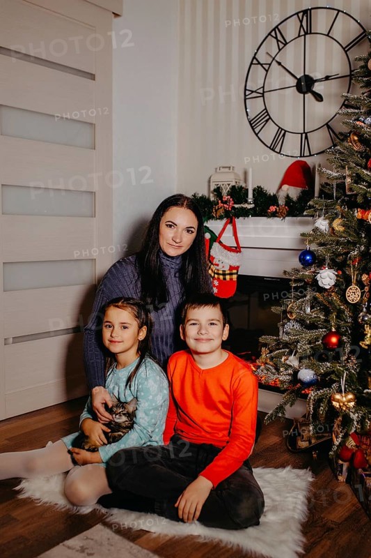 Family group portrait showing a mother, children, and kitten in a festive christmas home setting.Belarus