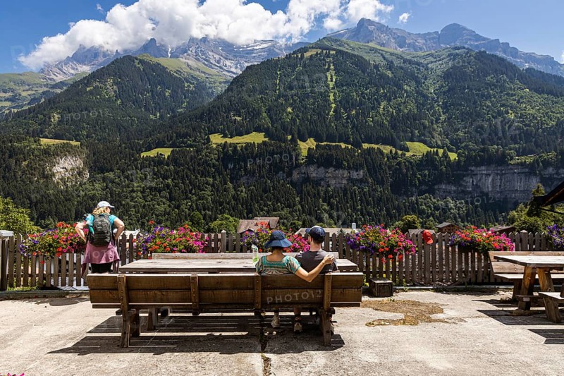 A couple sitting on a bench is enjoying the view on the mountains in Champery, a village in Switzerland by the French border