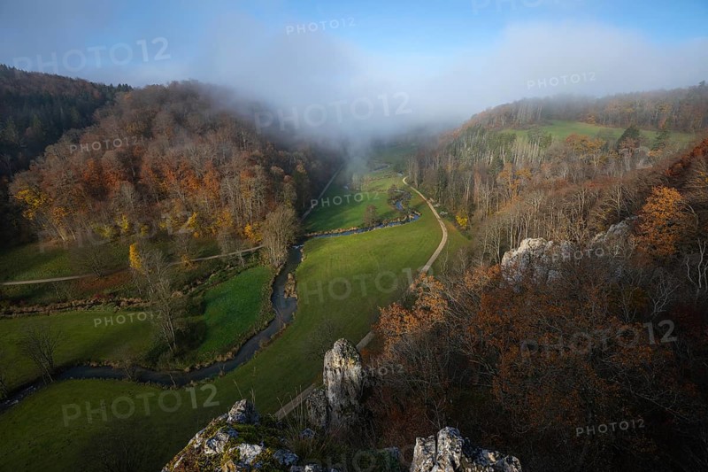Autumn landscape with rising fog over the Grosse Lauter river loop in Lautertal at sunrise. View from above of the picturesque valley with colorful deciduous forest and rolling hills, Großes Lautertal, Baden-Württemberg, Germany
