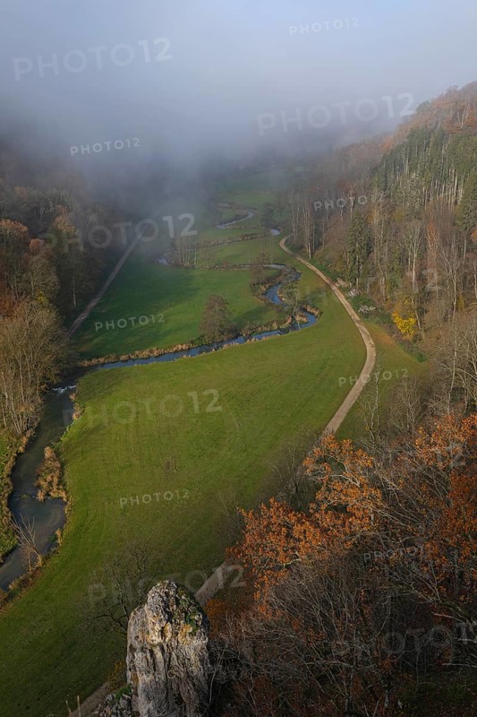 Autumn landscape with rising fog over the Grosse Lauter river loop in Lautertal at sunrise. View from above of the picturesque valley with colorful deciduous forest and rolling hills, Großes Lautertal, Baden-Württemberg, Germany