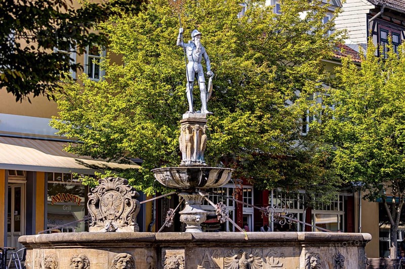 Fountain with an impressive warrior statue in a municipal park with trees, statue and memorial in the old town of Arnstadt in Thuringia