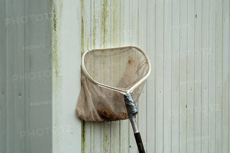 Borken-Hoxfeld, NRW, Germany, A cleaning tool leans against a dirty wall, showing signs of recent use. The metal handle reflects a typical day in a city where maintenance is necessary for cleanliness