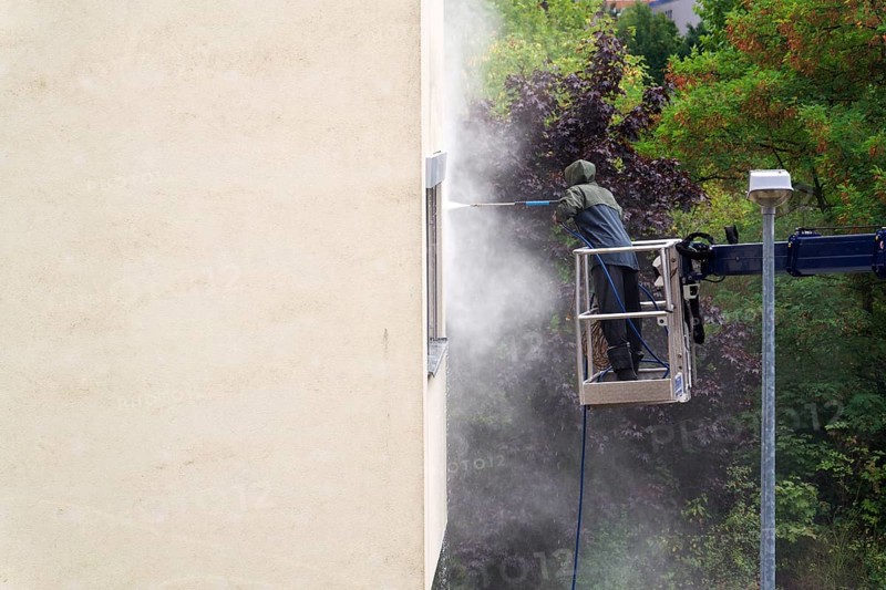 Unrecognizable man cleaning facade surface from lifting platform with high pressure stream of water Prague, Czech republic